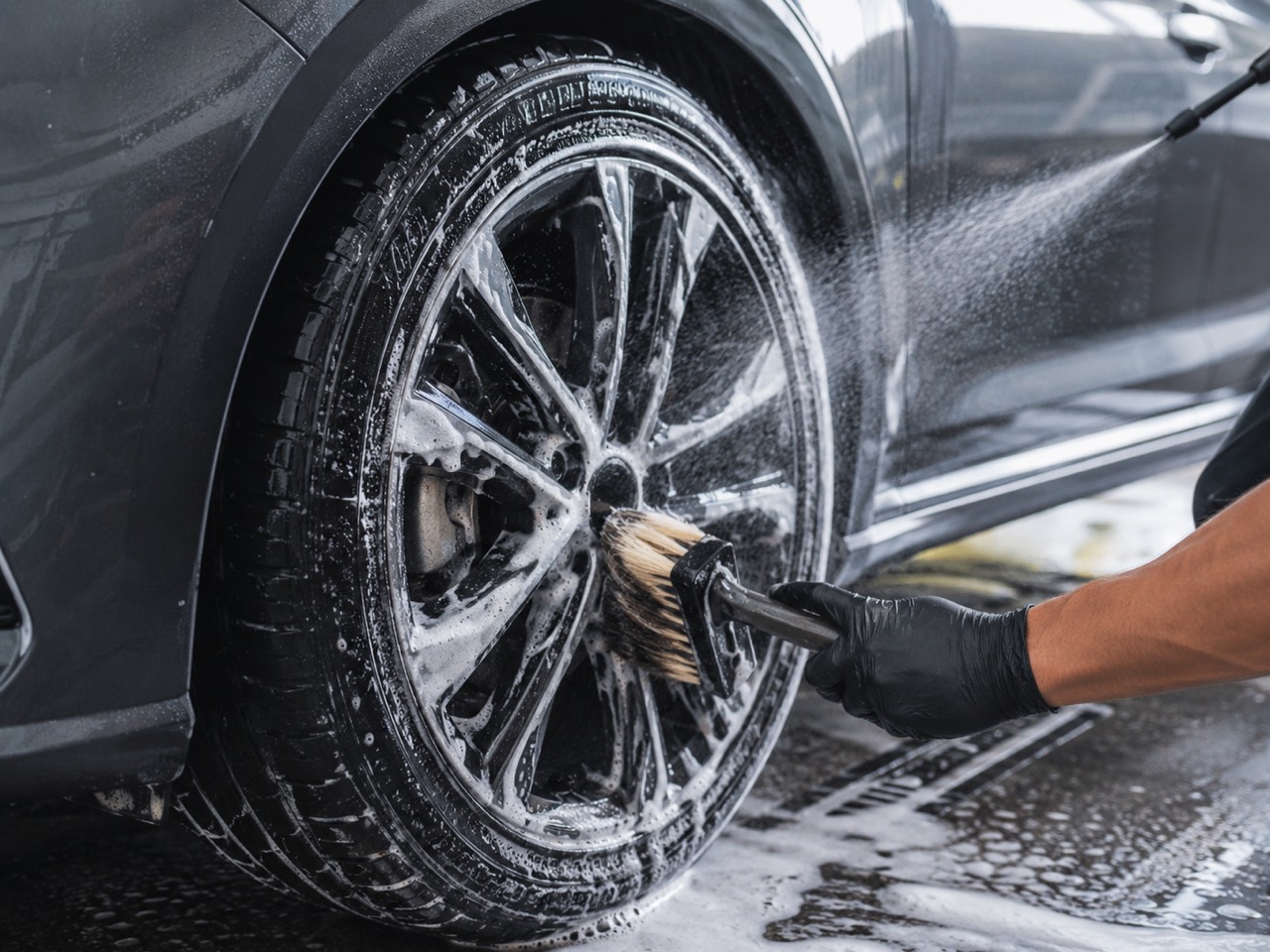 Wheel and tire being cleaned with brush and rinse water